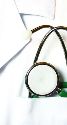 A stethoscope hangs from the pocket of a white lab coat, which is accompanied by a bright red necktie.